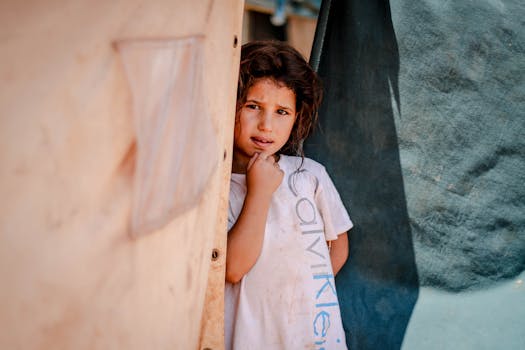 A young girl standing outside a tent in a Syrian refugee camp in Idlib.